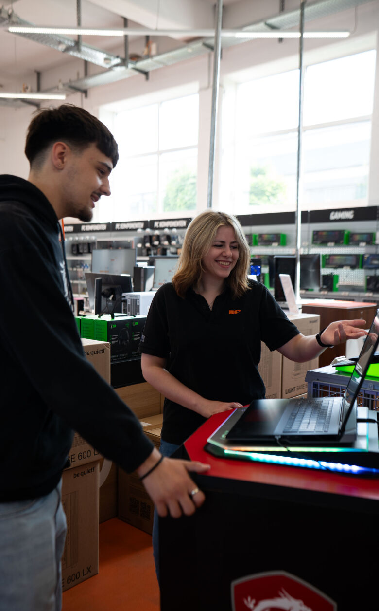 A woman and a man are looking at a notebook.