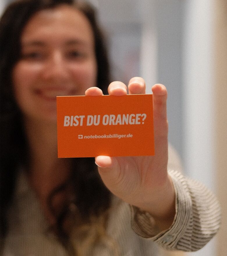 Woman holding card labelled Are you orange